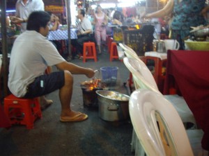 A guy roasting live prawns, shortly before one of them hopped right off the grill